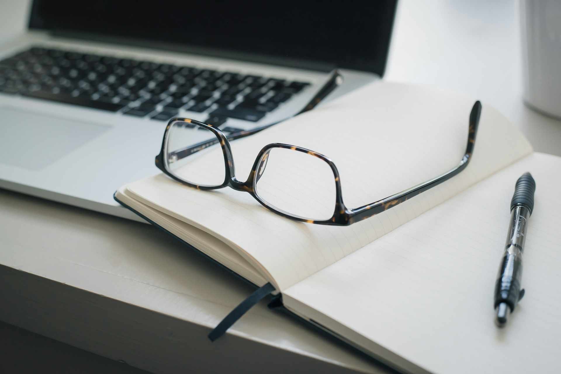 Espace de travail contemporain : ordinateur portable, carnet ouvert, lunettes et stylo